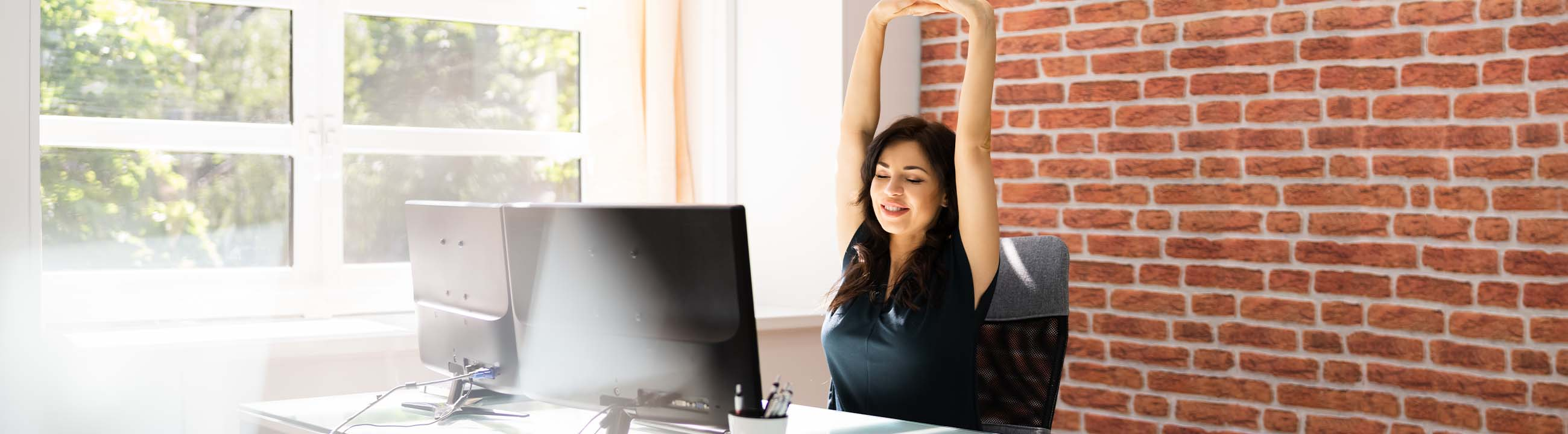 Vrouw zit op kantoor en strekt haar armen